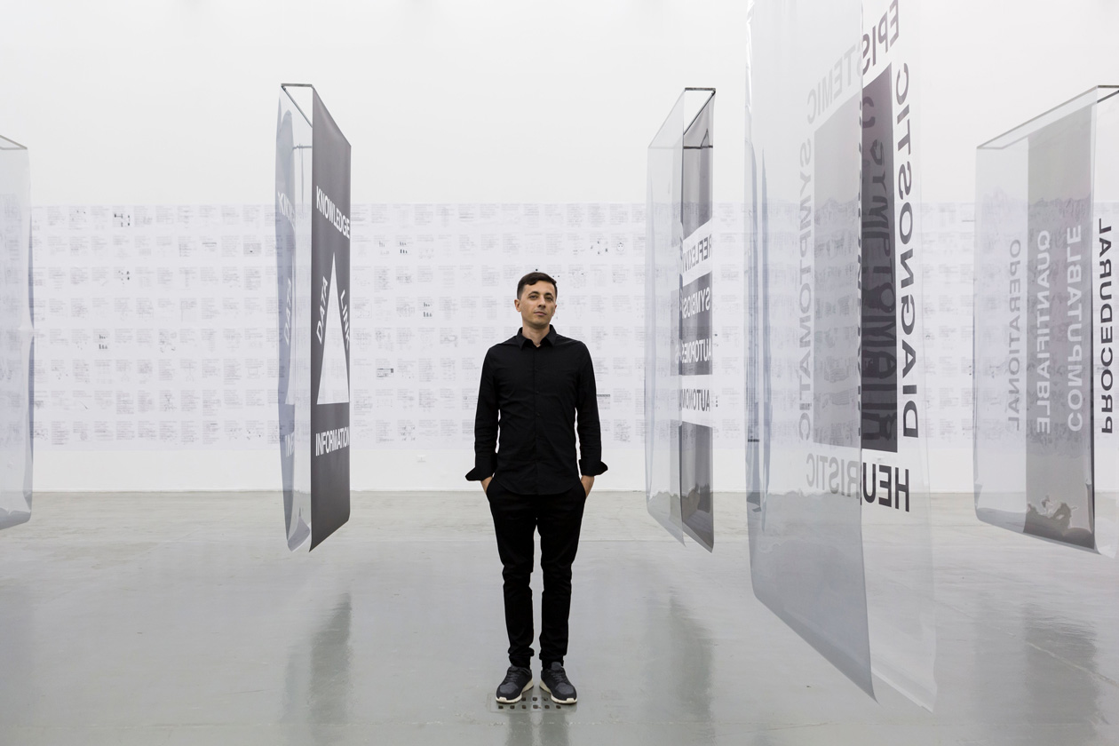 Paolo Cirio in front of his artwork, Foundations, at Giorgio Persano Gallery in Turin, Italy, 2019. Image courtesy of Paolo Cirio, photo Nicola Morittu. https://paolocirio.net/work/foundations/